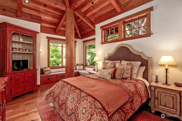 bedroom featuring light hardwood / wood-style flooring, wood ceiling, and vaulted ceiling with beams