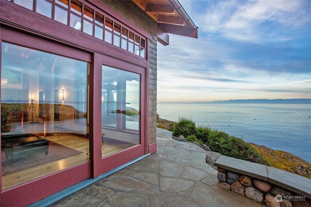 exterior entry at dusk with french doors, a patio, and a water view