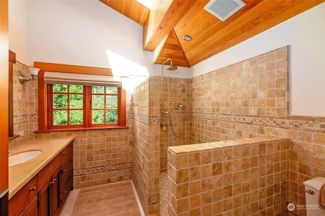 bathroom featuring vaulted ceiling with beams, vanity, tile walls, and a tile shower