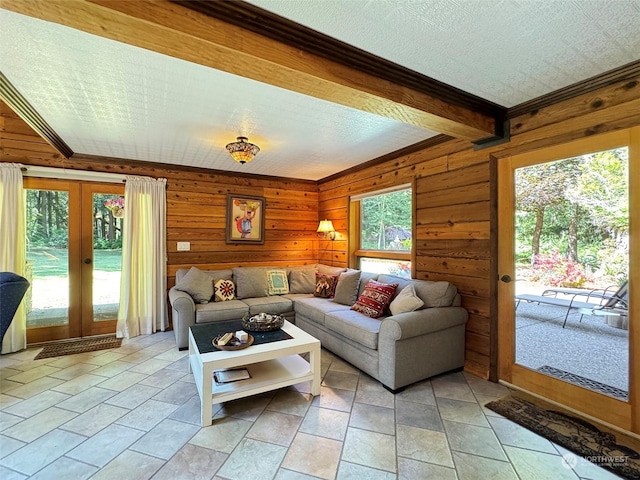 living room with crown molding, light tile patterned floors, wooden walls, and french doors