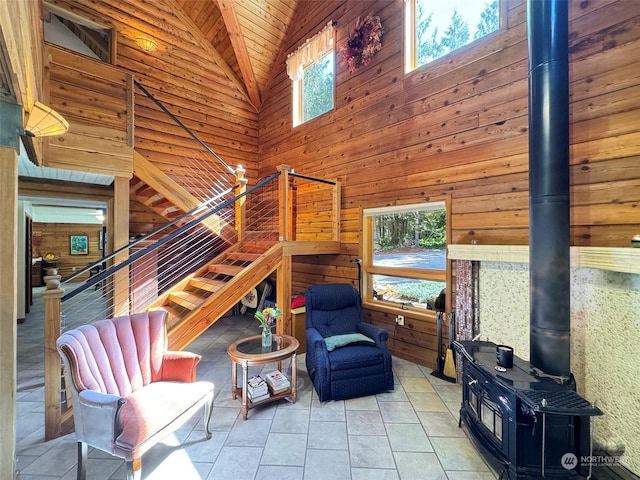 tiled living room featuring wood walls, a healthy amount of sunlight, high vaulted ceiling, and a wood stove