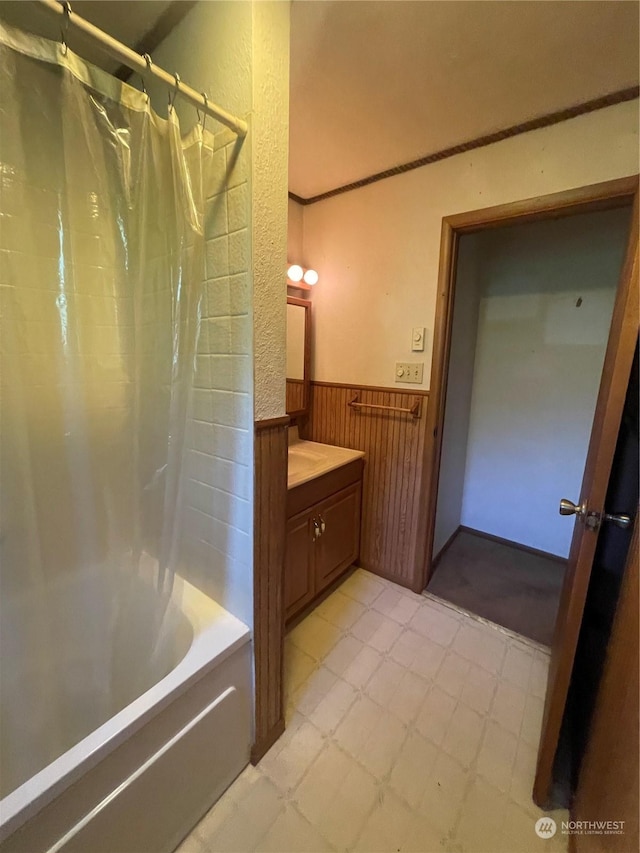 bathroom with vanity, wood walls, and shower / tub combo with curtain