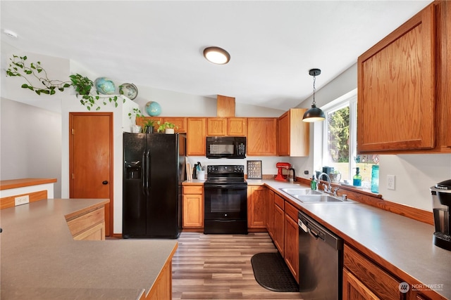 kitchen featuring sink, black appliances, light hardwood / wood-style floors, hanging light fixtures, and lofted ceiling