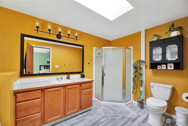 bathroom with a skylight, walk in shower, hardwood / wood-style floors, toilet, and vanity