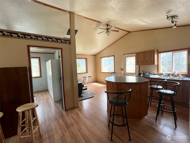 kitchen featuring a textured ceiling, hardwood / wood-style floors, lofted ceiling, and a kitchen bar