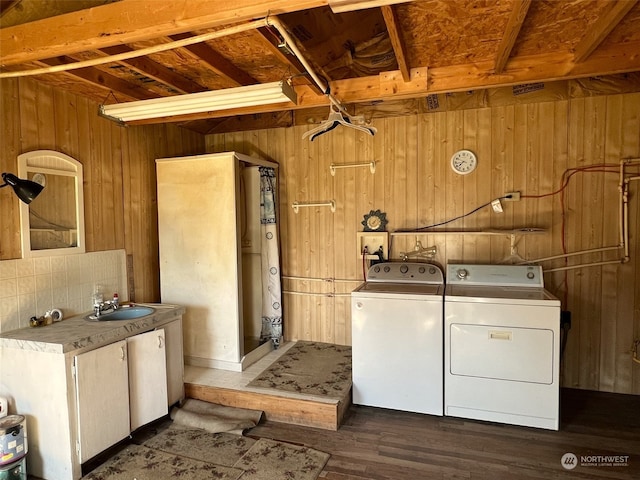 laundry area featuring washer and clothes dryer, hookup for a washing machine, dark wood-type flooring, sink, and wooden walls