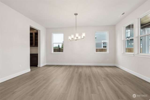 unfurnished dining area featuring a chandelier and light wood-type flooring