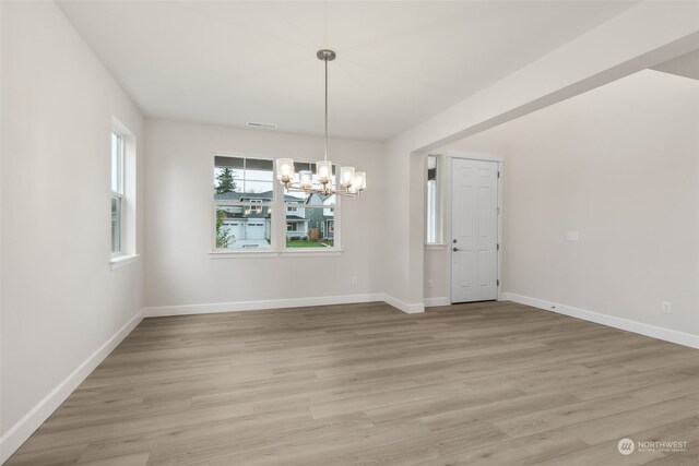 unfurnished dining area featuring a chandelier and light hardwood / wood-style flooring