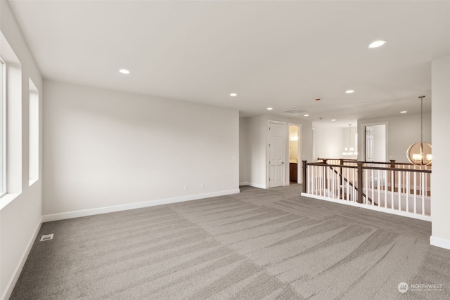 carpeted empty room featuring an inviting chandelier