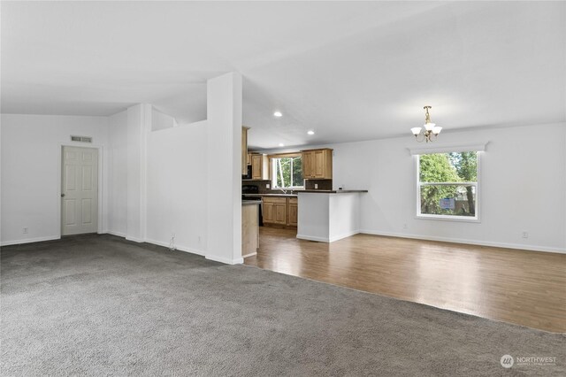 unfurnished living room featuring dark carpet and a chandelier