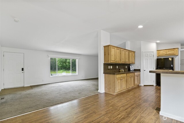 kitchen with tasteful backsplash, dark hardwood / wood-style floors, and black fridge