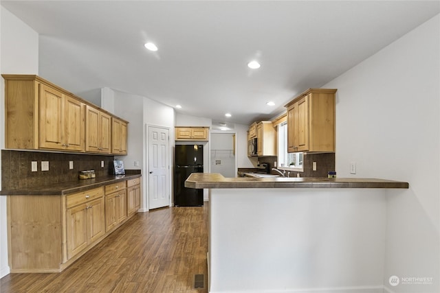 kitchen featuring tasteful backsplash, dark wood-type flooring, kitchen peninsula, and black appliances