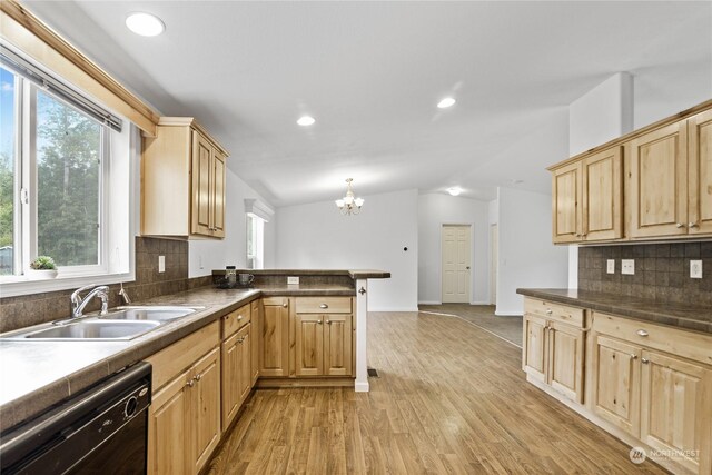 kitchen with lofted ceiling, light brown cabinetry, sink, dishwasher, and kitchen peninsula