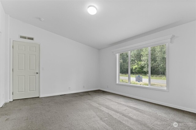 carpeted empty room featuring vaulted ceiling