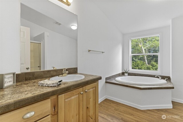 bathroom featuring vanity, wood-type flooring, separate shower and tub, and vaulted ceiling