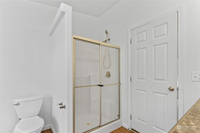 bathroom with hardwood / wood-style floors, toilet, and walk in shower