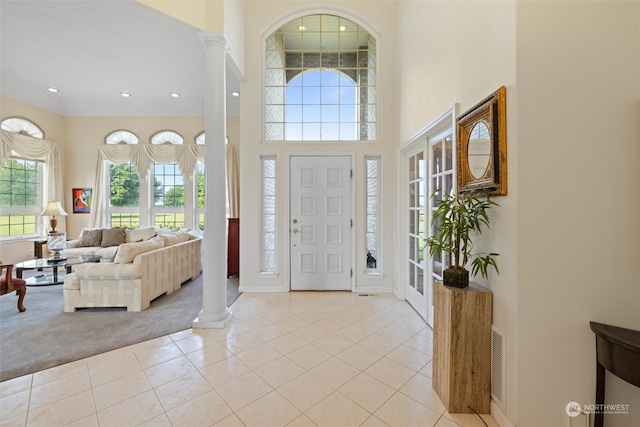 carpeted foyer entrance with a towering ceiling and ornate columns