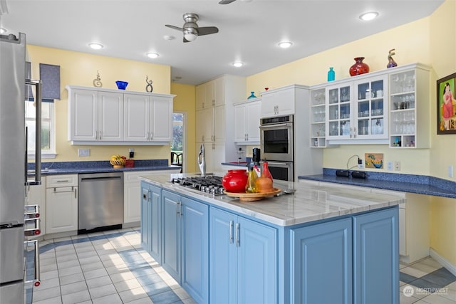 kitchen with appliances with stainless steel finishes, blue cabinets, white cabinetry, and ceiling fan