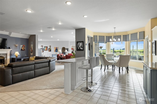 kitchen with a textured ceiling, a breakfast bar area, a notable chandelier, hanging light fixtures, and light carpet