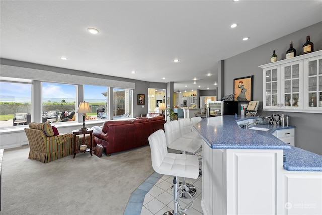 interior space featuring a breakfast bar, white cabinets, dark stone countertops, and light colored carpet