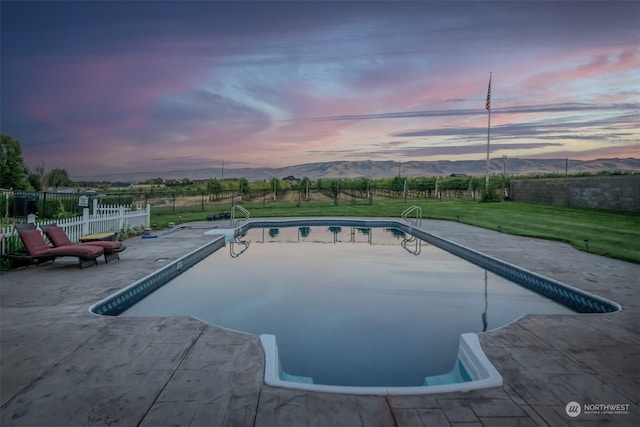 pool at dusk with a mountain view and a lawn