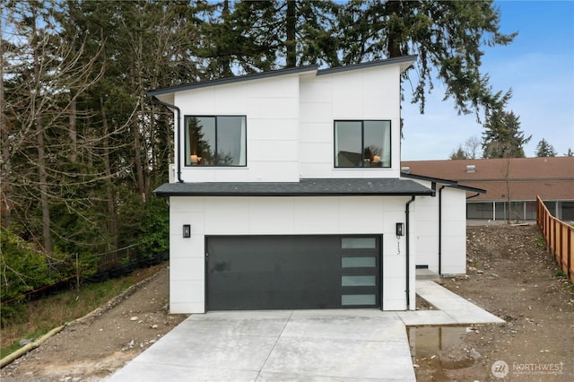 modern home with roof with shingles, stucco siding, concrete driveway, an attached garage, and fence