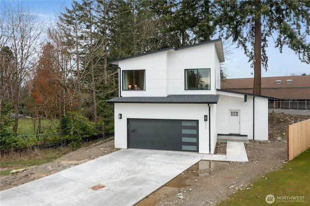 view of front facade featuring concrete driveway, roof with shingles, an attached garage, fence, and stucco siding