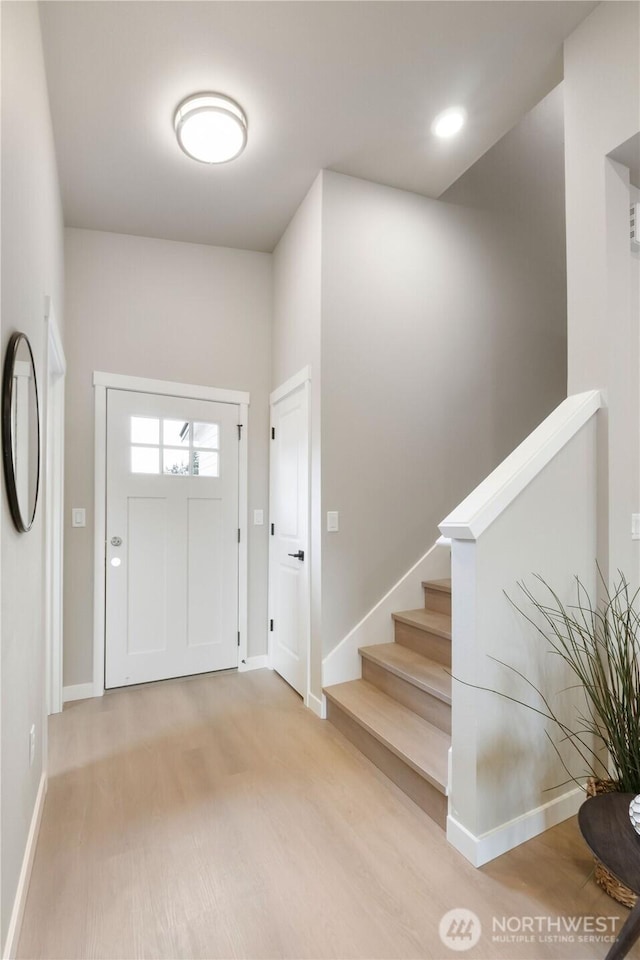 entryway featuring wood finished floors, baseboards, and stairs