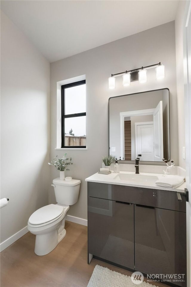 bathroom featuring baseboards, vanity, toilet, and wood finished floors