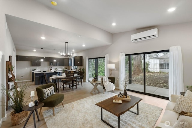 living area featuring light wood-type flooring, recessed lighting, an AC wall unit, and baseboards