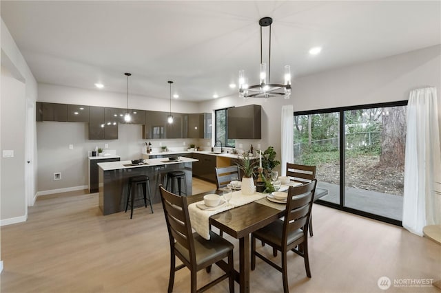 dining space featuring light wood-type flooring, an inviting chandelier, baseboards, and recessed lighting