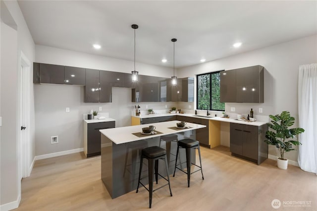 kitchen with a center island, decorative light fixtures, light countertops, modern cabinets, and light wood-type flooring