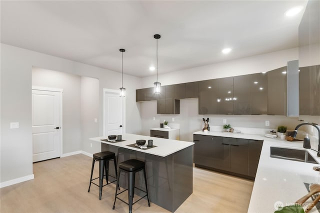 kitchen featuring a sink, hanging light fixtures, light countertops, light wood-type flooring, and modern cabinets