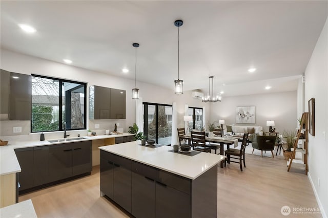 kitchen with pendant lighting, light countertops, a kitchen island, a sink, and modern cabinets