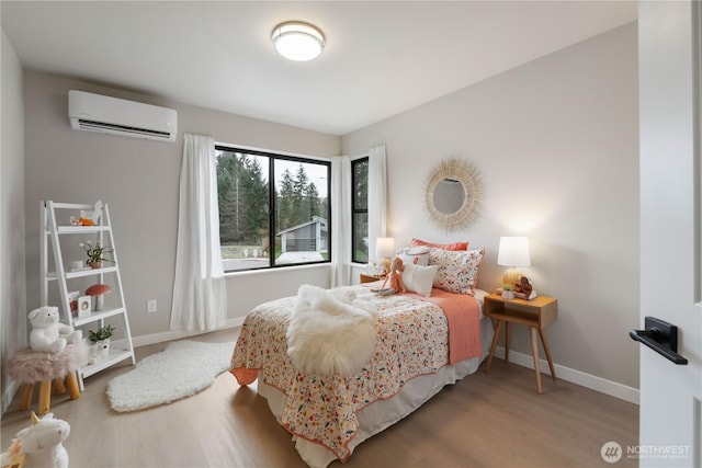 bedroom featuring an AC wall unit, wood finished floors, and baseboards