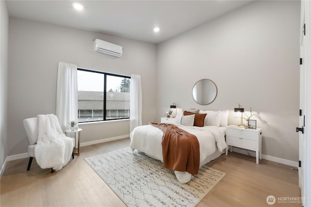 bedroom featuring recessed lighting, baseboards, light wood finished floors, and a wall mounted AC