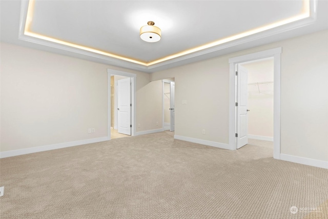 carpeted spare room with a raised ceiling