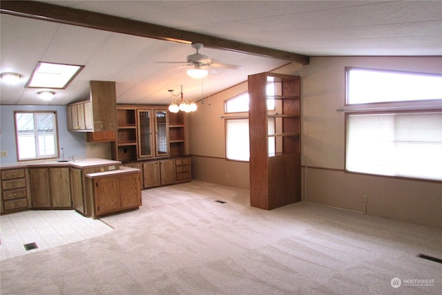 kitchen with light carpet, lofted ceiling with beams, ceiling fan with notable chandelier, and hanging light fixtures