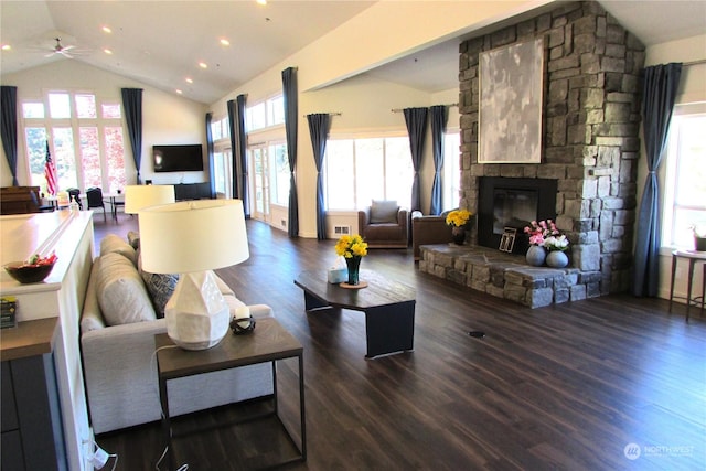 living room with vaulted ceiling, a stone fireplace, ceiling fan, and a healthy amount of sunlight