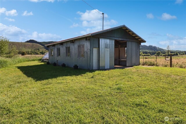 view of outdoor structure with a lawn, a mountain view, and a rural view