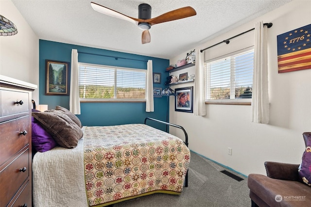 bedroom featuring carpet flooring, multiple windows, ceiling fan, and a textured ceiling