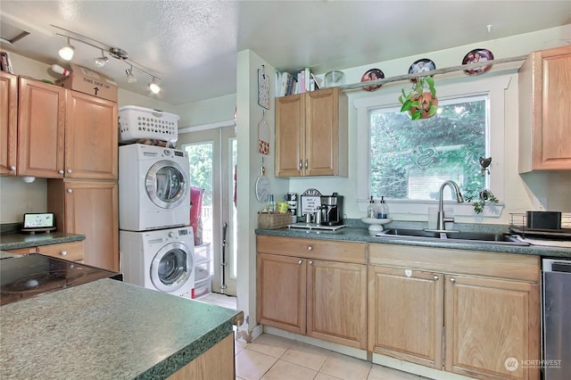 kitchen featuring light tile patterned floors, a textured ceiling, stacked washer / dryer, and sink