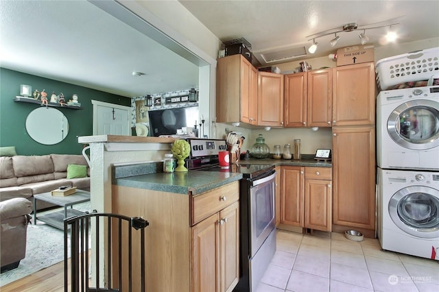 kitchen with stainless steel electric stove, stacked washing maching and dryer, and light tile patterned floors