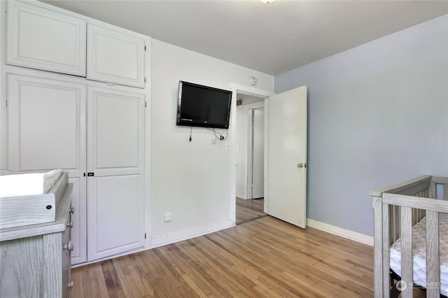 unfurnished bedroom with light hardwood / wood-style floors and a nursery area