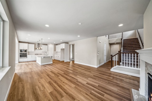 unfurnished living room featuring sink and light hardwood / wood-style floors