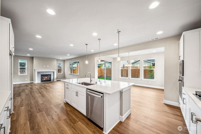 kitchen featuring appliances with stainless steel finishes, sink, hardwood / wood-style floors, white cabinets, and a kitchen island with sink