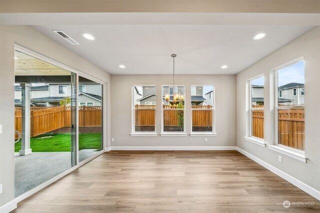 unfurnished dining area with a notable chandelier, wood-type flooring, and a wealth of natural light