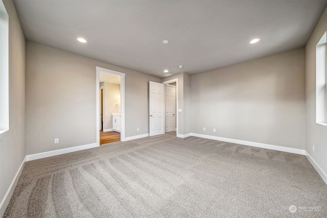 unfurnished bedroom with connected bathroom and carpet floors