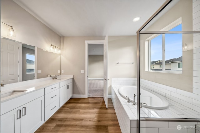 bathroom featuring vanity, hardwood / wood-style flooring, a wealth of natural light, and tiled bath