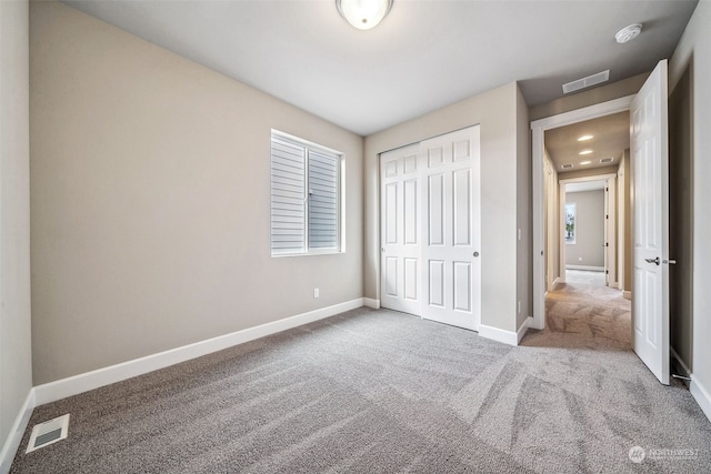 unfurnished bedroom with a closet and light carpet